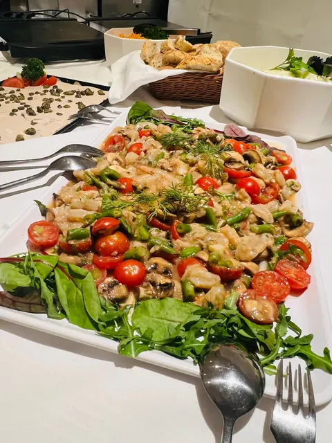 Platte mit Garnelensalat, Tomaten und Rucola auf einem Büfett