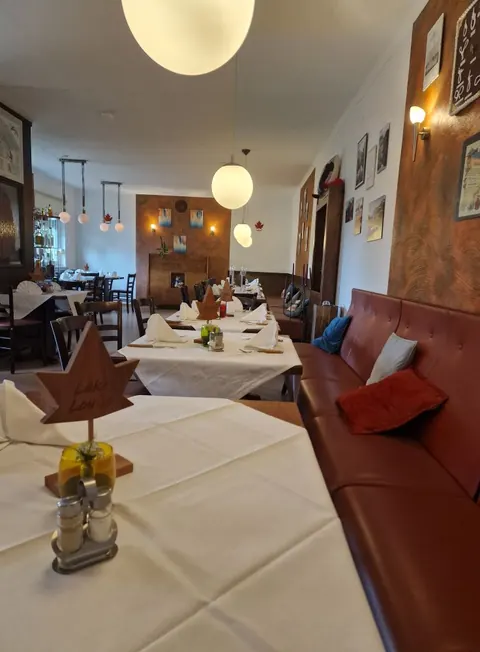 Gedeckte Tische mit weißen Decken und Bank an der Wand