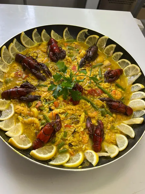 Paella mit Langustinen und Zitronenscheiben in der Pfanne