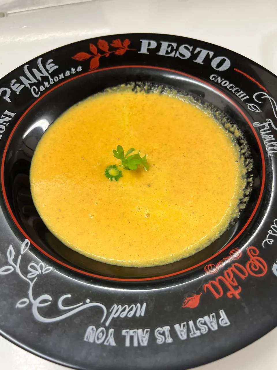 Orangefarbene Cremesuppe in einem schwarzen Teller